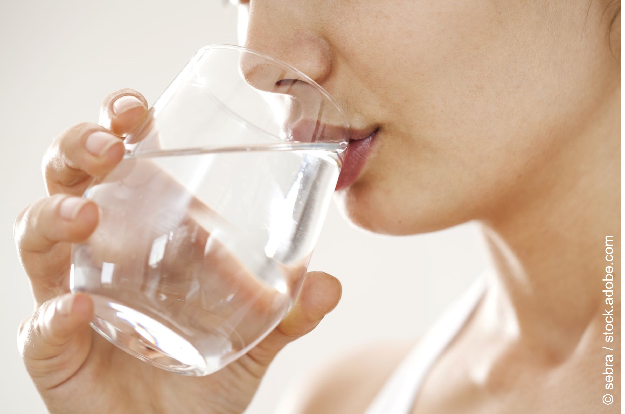 Eine Frau trinkt ein Glas Wasser. 